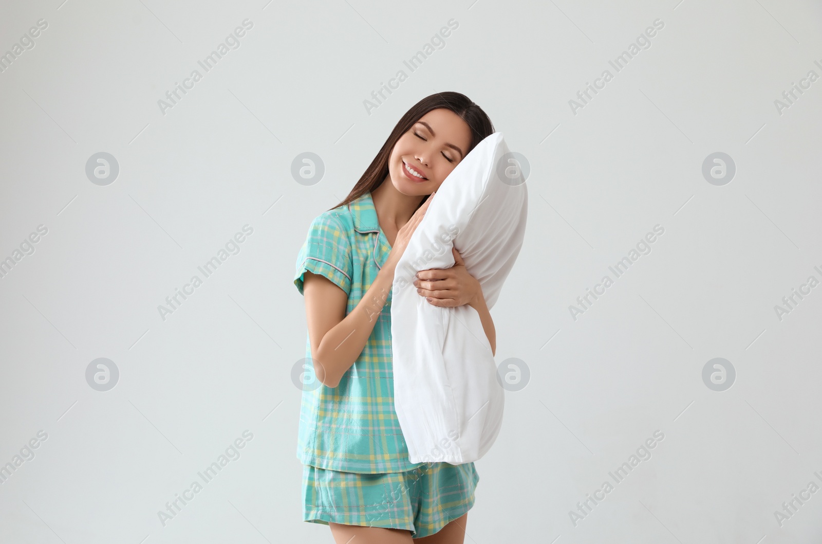 Photo of Beautiful Asian woman with pillow on light grey background. Bedtime