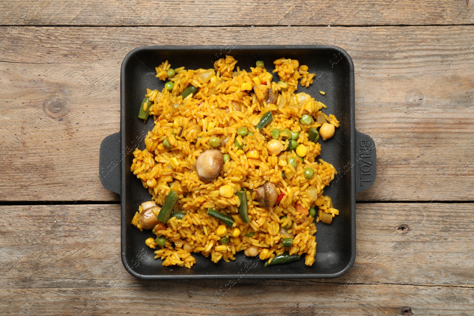 Photo of Delicious rice pilaf with vegetables on wooden table, top view