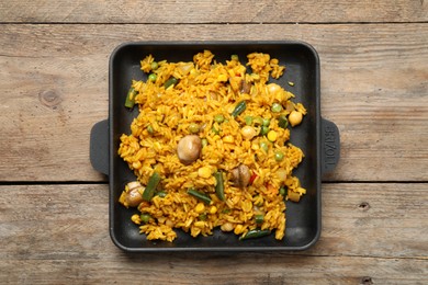 Photo of Delicious rice pilaf with vegetables on wooden table, top view