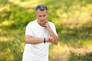 Photo of Man checking pulse outdoors on sunny day