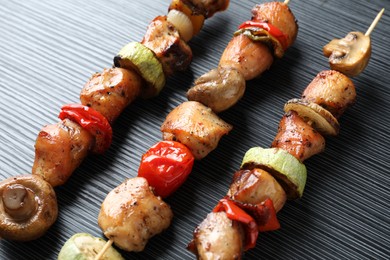 Photo of Delicious shish kebabs with vegetables on black table, closeup