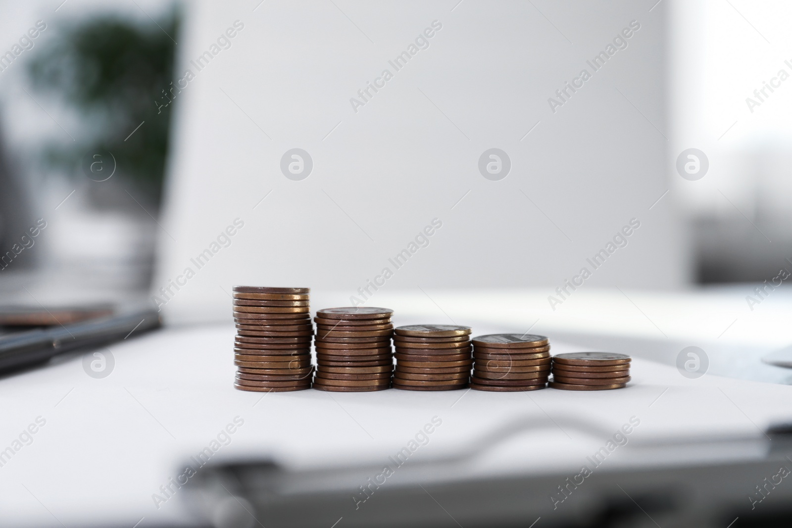 Photo of Stacks of coins on table against blurred background