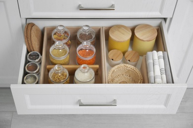 Photo of Open drawer with different jars indoors. Order in kitchen