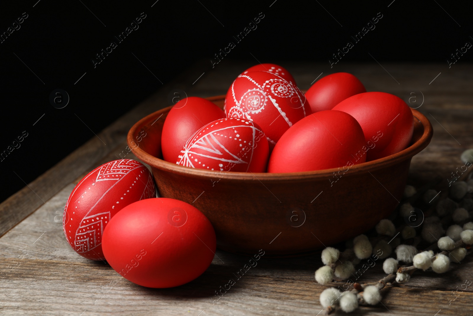 Photo of Wooden bowl with red painted Easter eggs on table