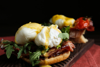 Delicious eggs Benedict served on wooden board, closeup