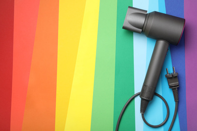 Photo of Hair dryer on rainbow background, top view with space for text. Professional hairdresser tool