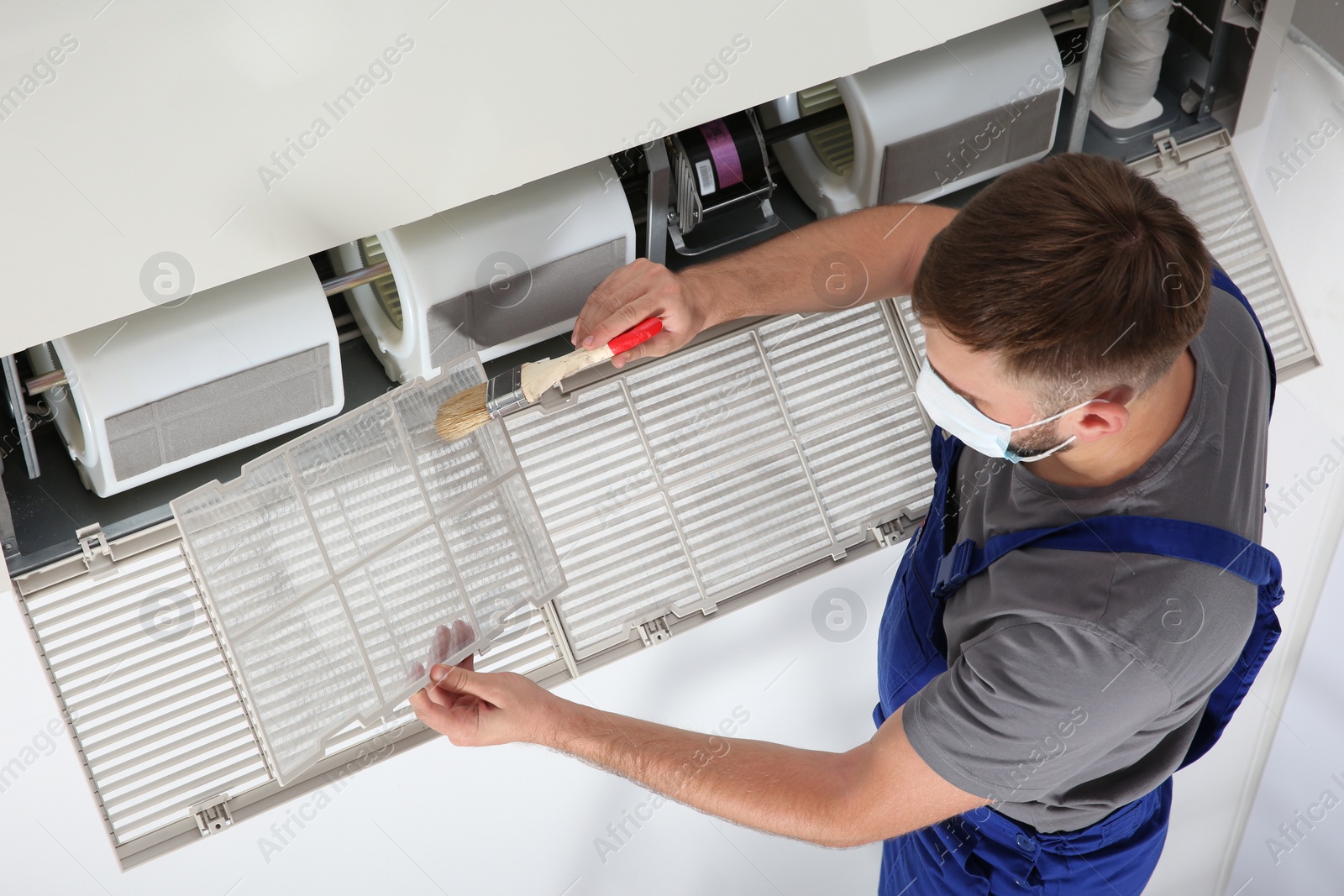 Photo of Young male technician cleaning air conditioner indoors