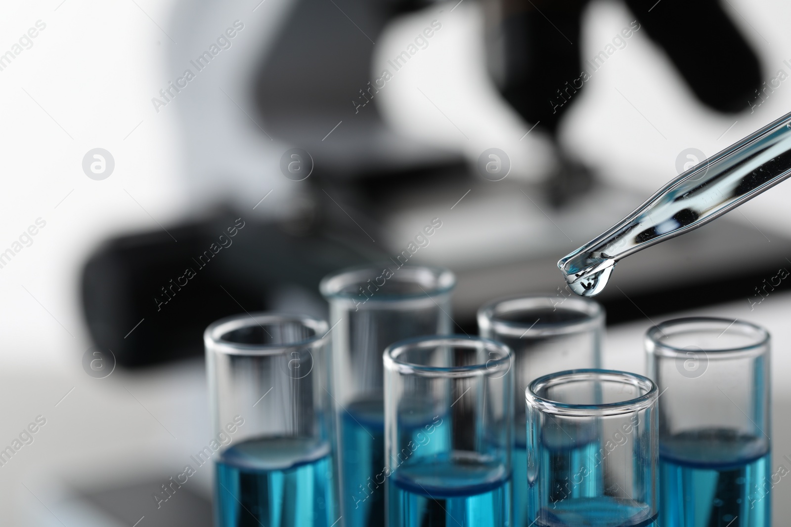 Photo of Dripping liquid from pipette into test tube in laboratory, closeup. Space for text