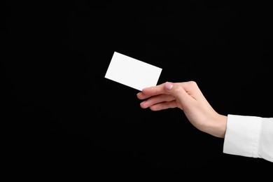 Woman holding blank business card on black background, closeup. Space for text