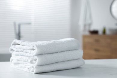 Stacked bath towels on white table indoors. Space for text