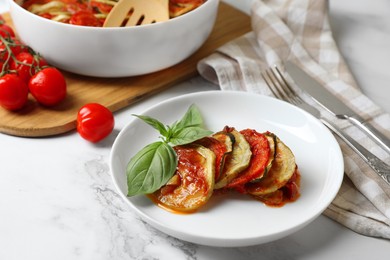 Photo of Delicious ratatouille served with basil on white marble table, closeup