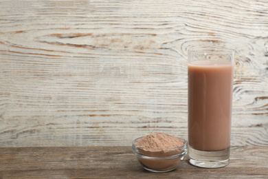 Photo of Protein shake and powder on wooden table, space for text