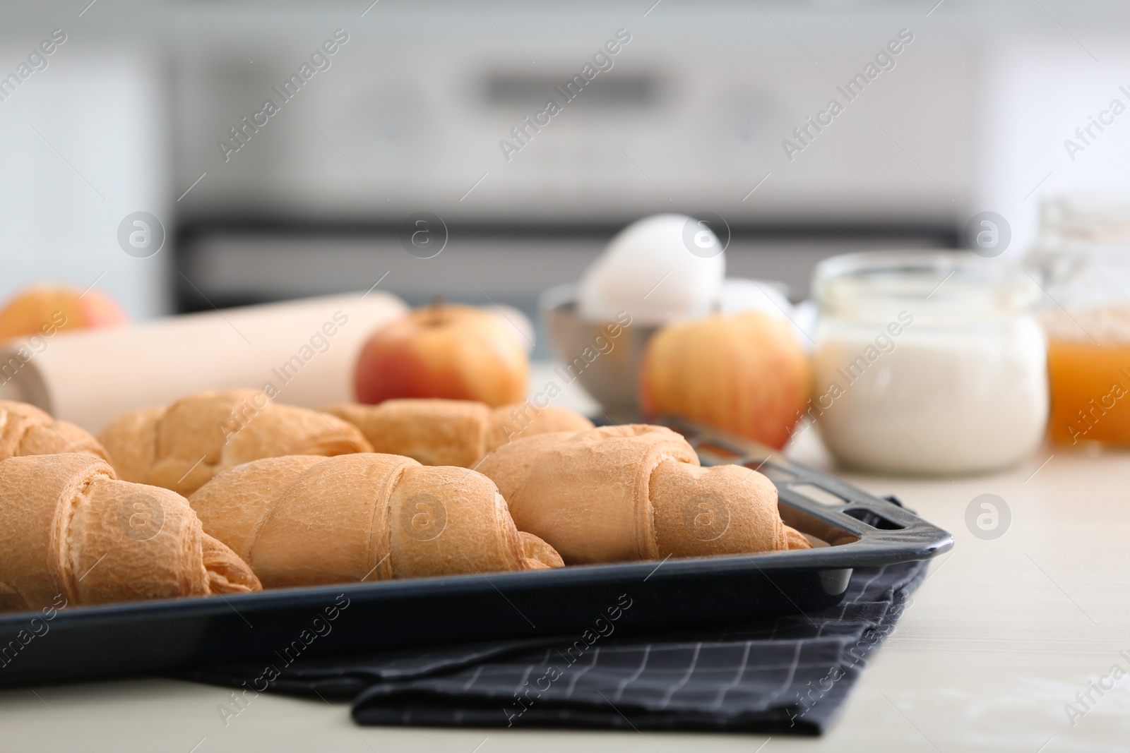 Photo of Baking tray with delicious croissants on kitchen table