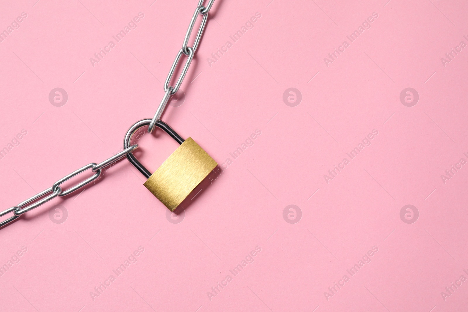 Photo of Steel padlock with chain on pink background, top view. Space for text