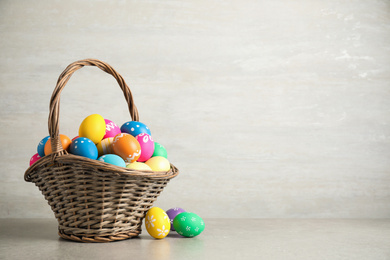 Photo of Basket with colorful Easter eggs on light grey background. Space for text