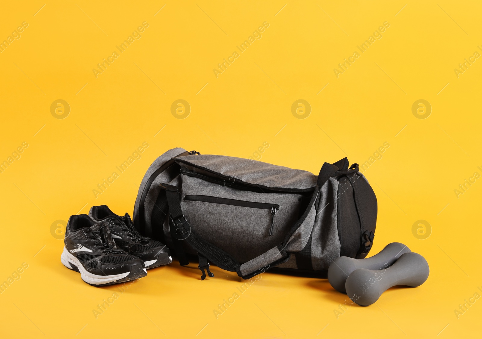 Photo of Sports bag and gym equipment on yellow background