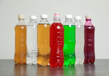 Photo of Bottles of soft drinks on table against grey background