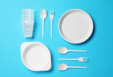 Photo of Flat lay composition with disposable tableware on light blue background