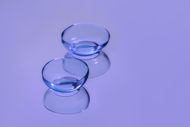 Photo of Pair of contact lenses on violet reflective surface