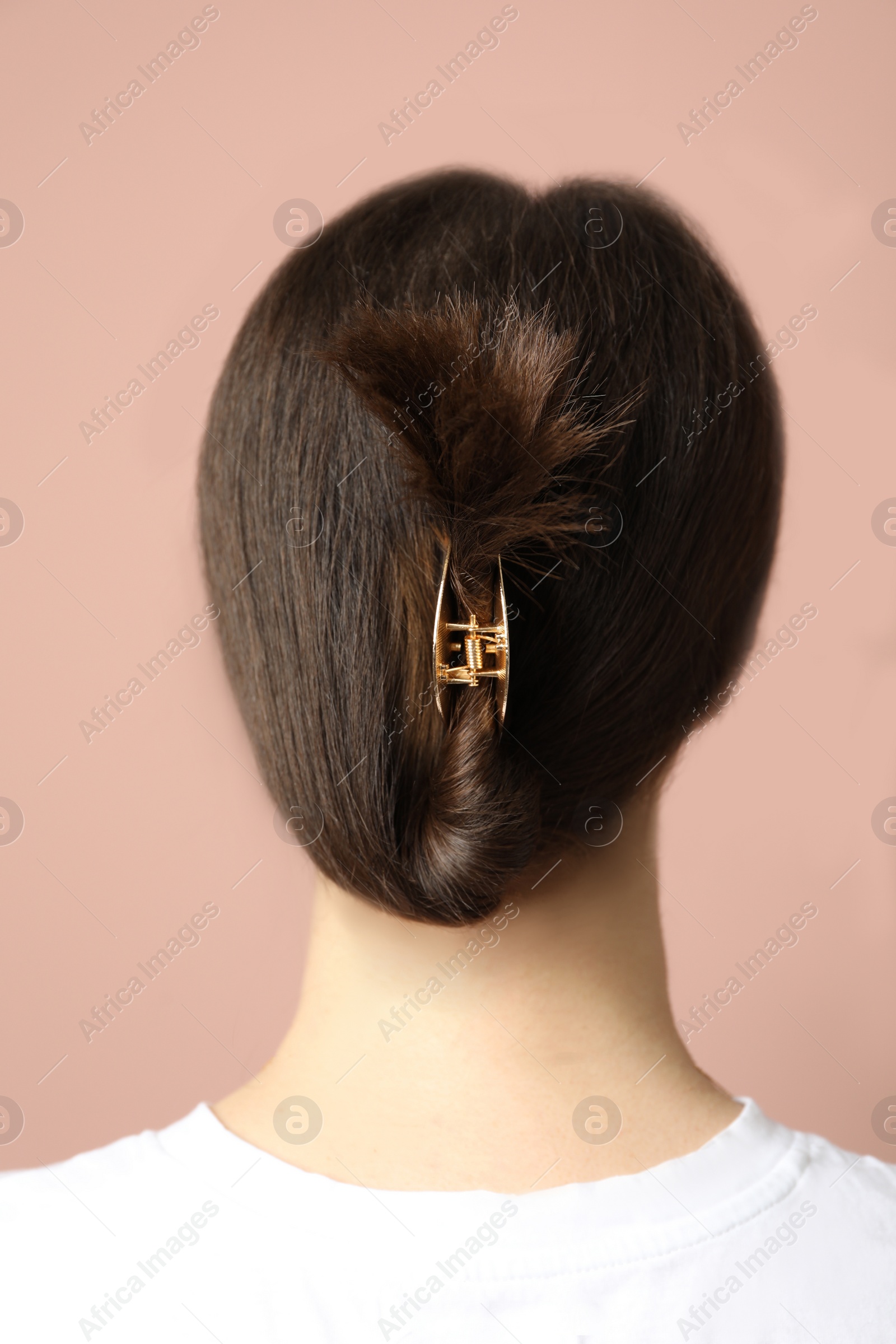 Photo of Young woman with beautiful gold hair claw on pink background, back view