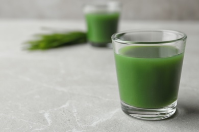 Photo of Glass of wheat grass juice on marble table. Space for text