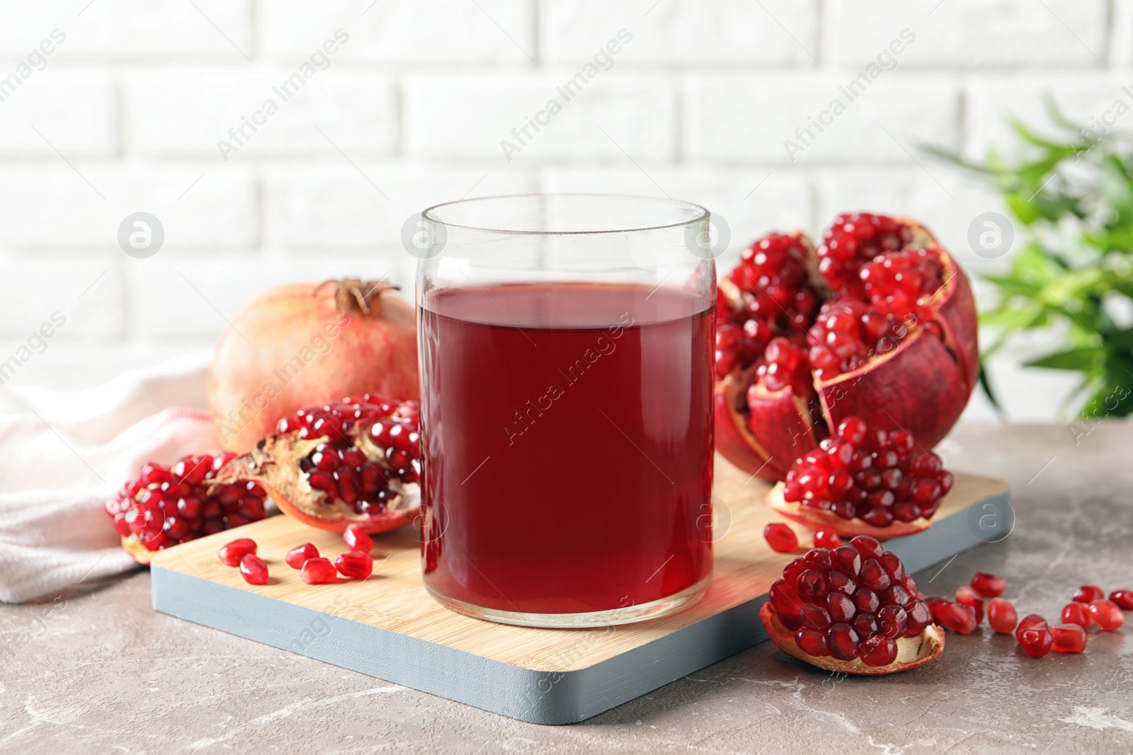 Photo of Composition with glass of fresh pomegranate juice on table