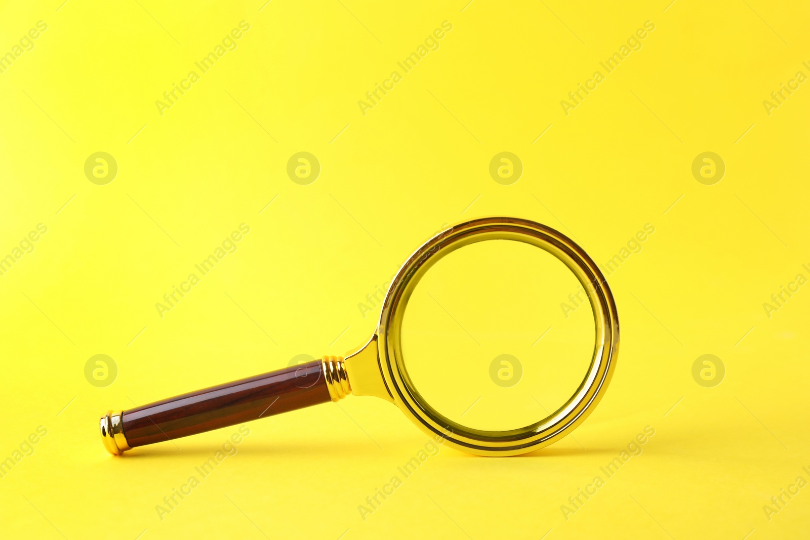 Photo of Magnifying glass with handle on yellow background