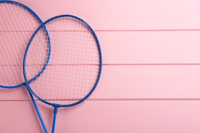 Photo of Rackets on pink wooden table, flat lay with space for text. Badminton equipment