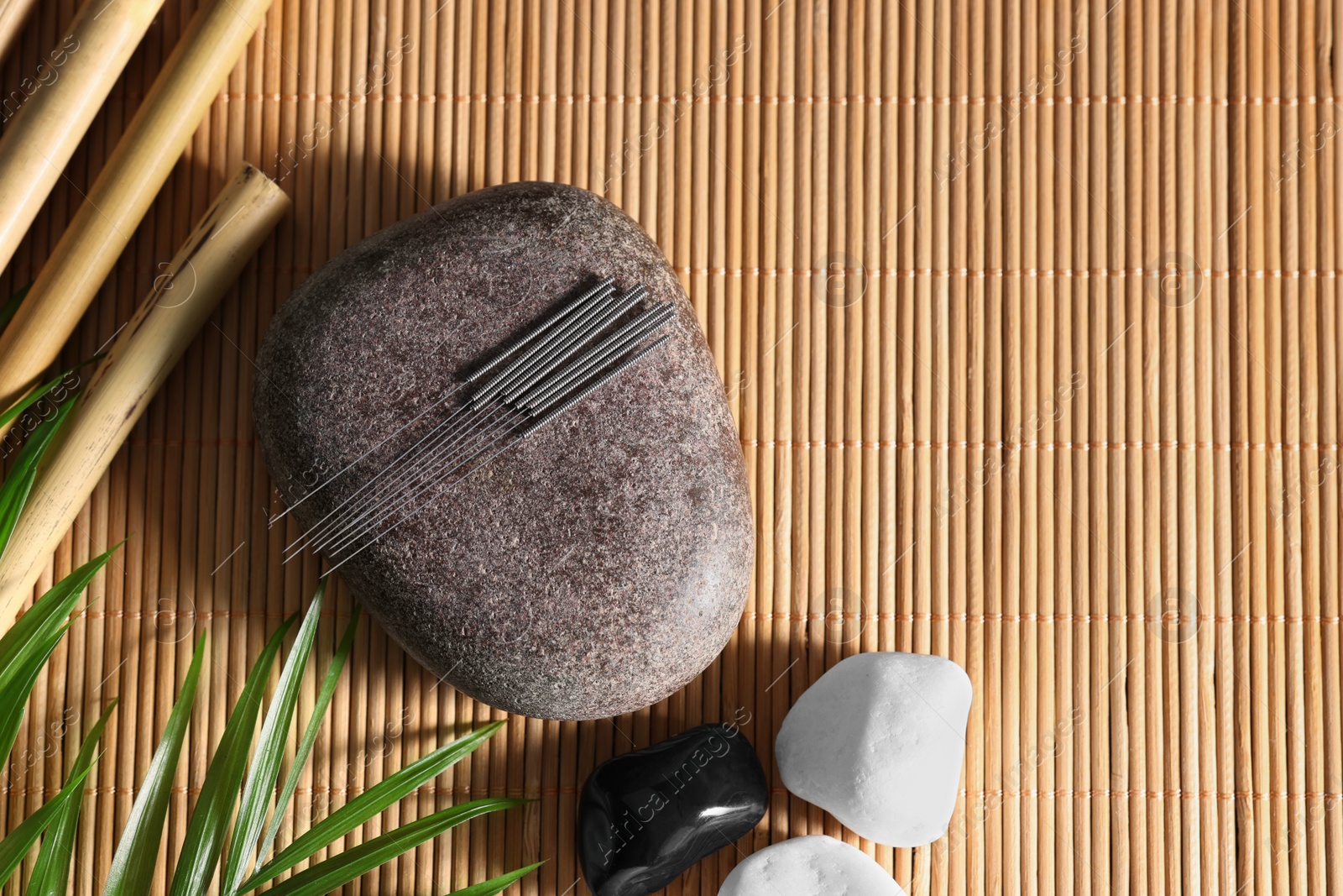 Photo of Flat lay composition with acupuncture needles on bamboo mat, space for text