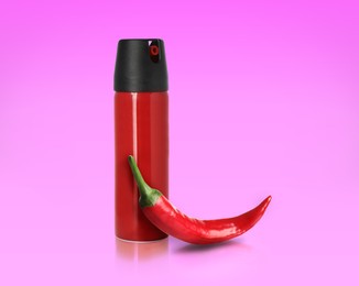 Bottle of pepper spray and red hot chilli on pink background