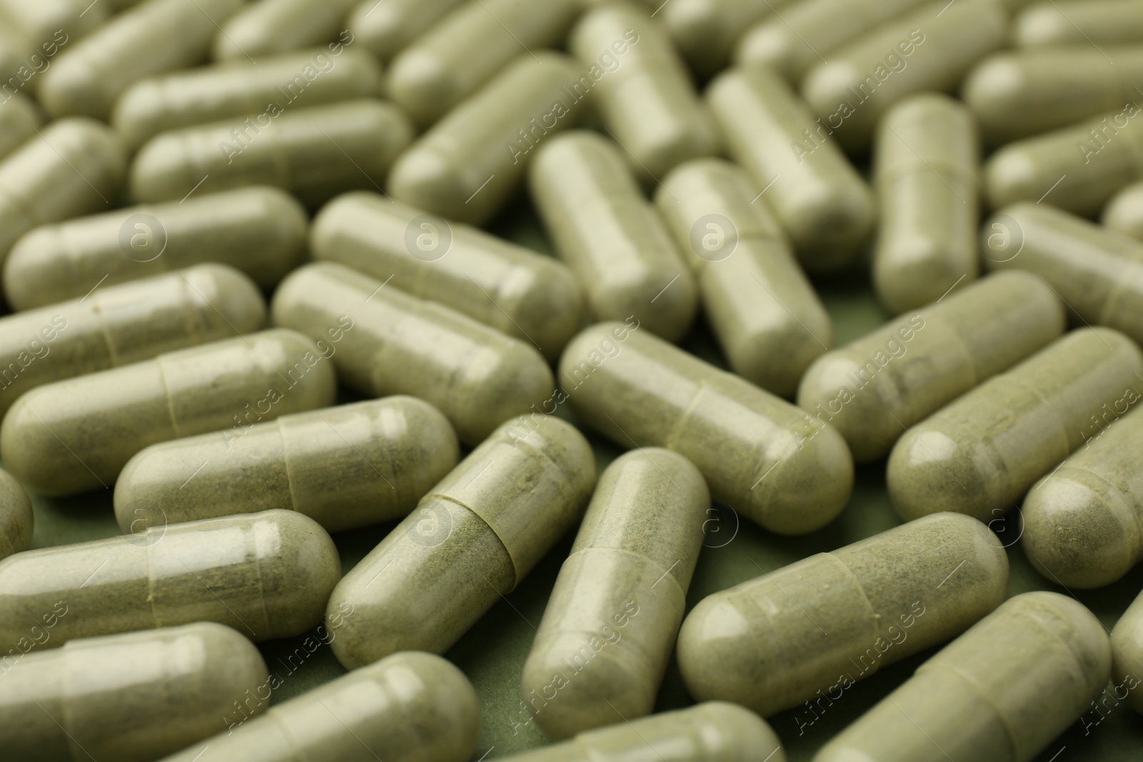 Photo of Many vitamin capsules on olive background, closeup