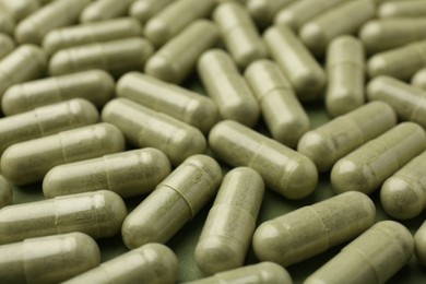 Photo of Many vitamin capsules on olive background, closeup