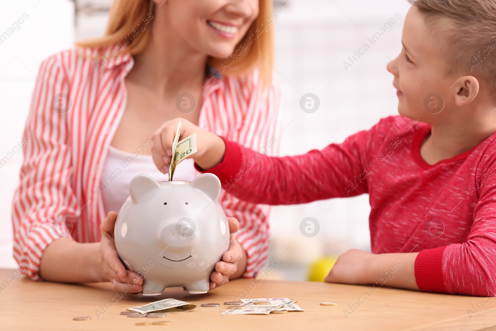 Photo of Family with piggy bank and money at table