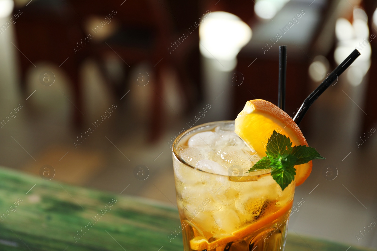 Photo of Glass of delicious cocktail with ice on blurred background, closeup