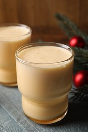 Photo of Glasses of delicious eggnog on table, closeup