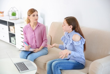 Photo of Female psychologist working with teenager girl in office