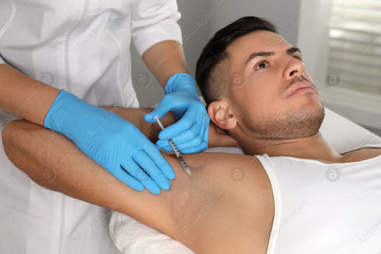 Photo of Cosmetologist injecting man's armpit in clinic. Treatment of hyperhidrosis