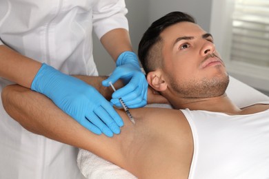 Photo of Cosmetologist injecting man's armpit in clinic. Treatment of hyperhidrosis