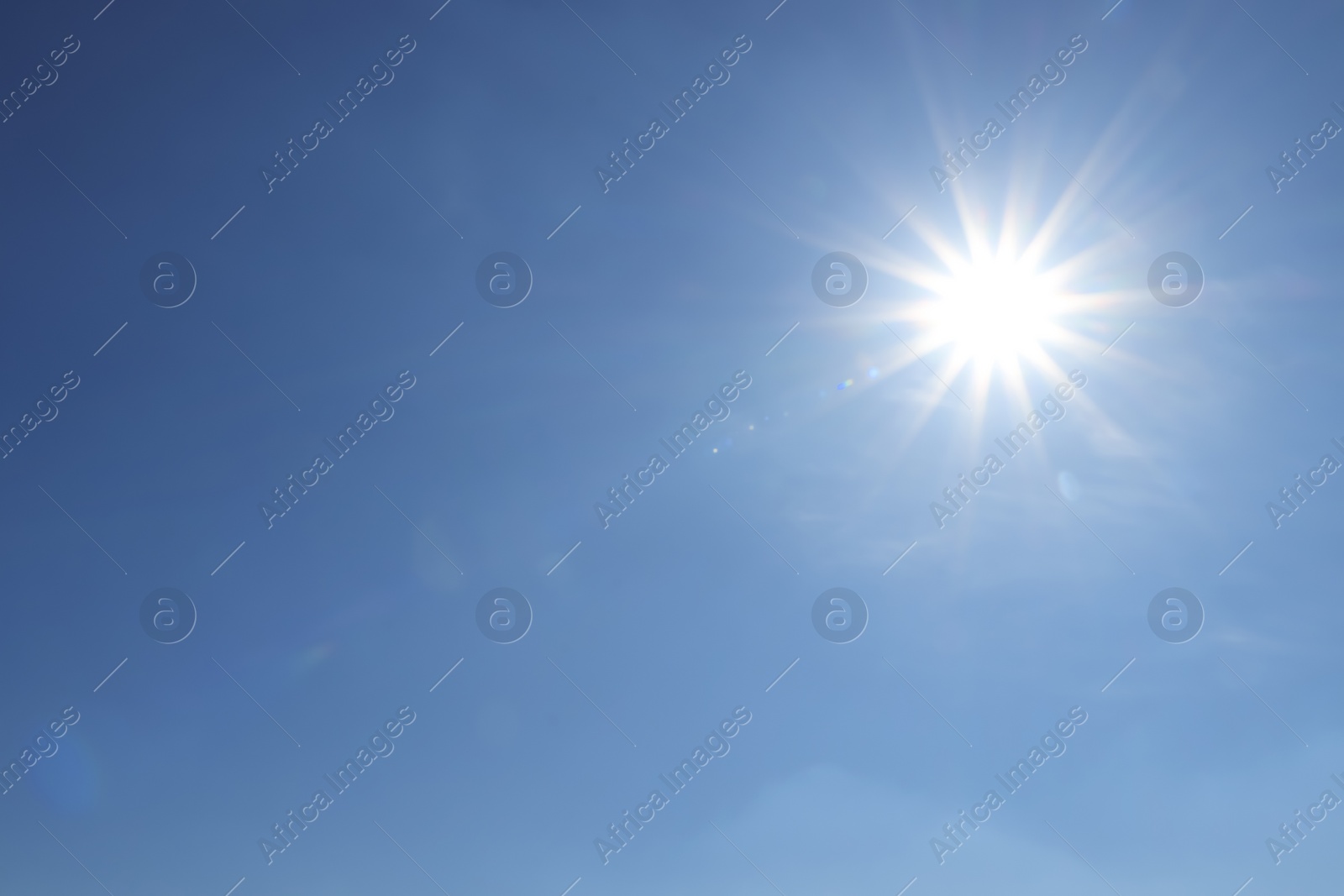 Photo of Bright sun in blue sky. Halo effect