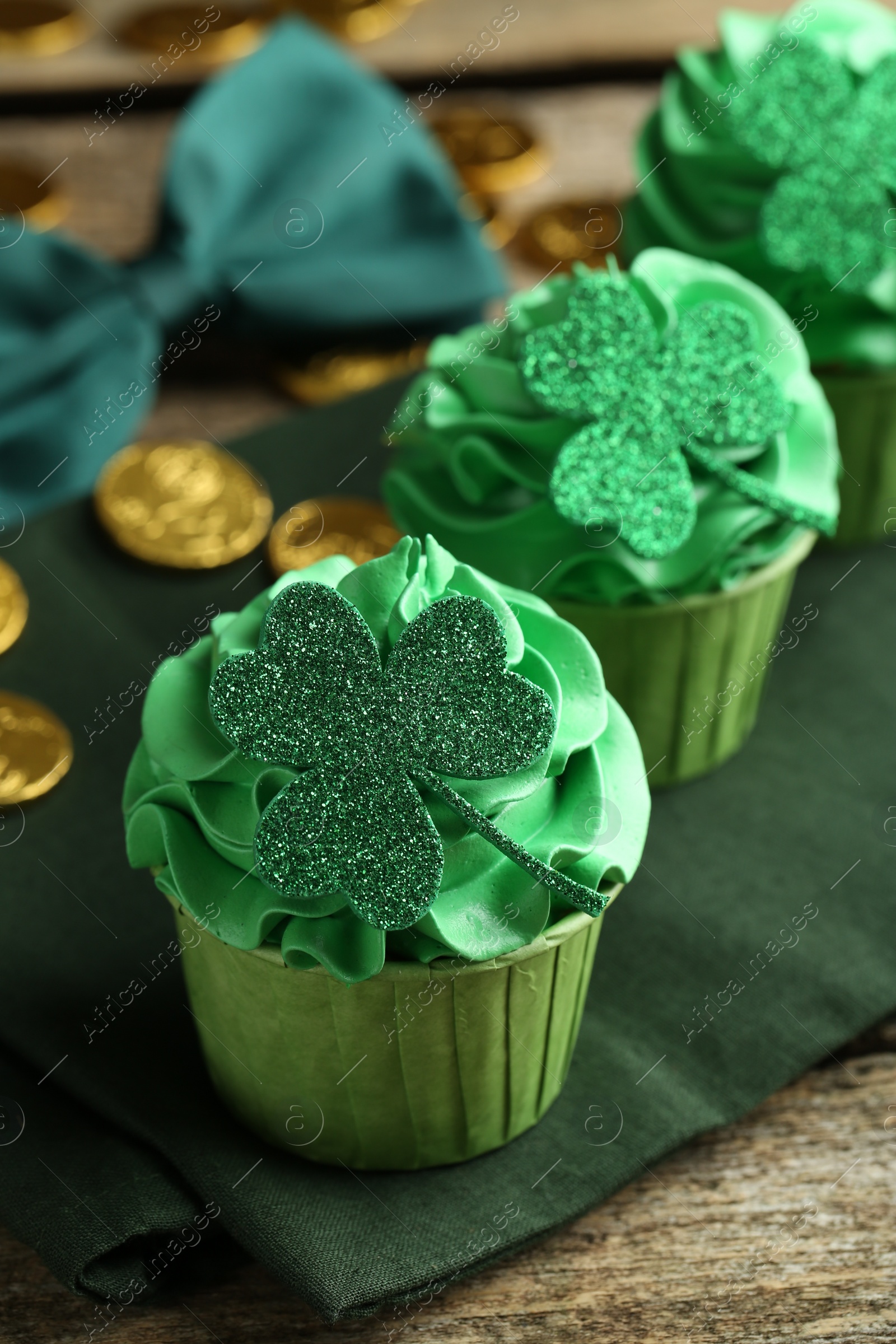 Photo of St. Patrick's day party. Tasty cupcakes with clover leaf toppers and green cream on wooden table, closeup