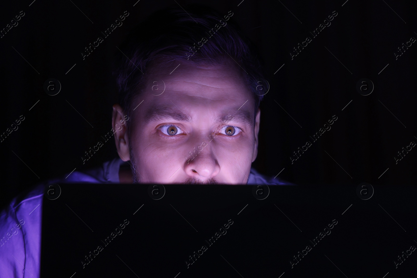 Photo of Man using computer at night, closeup. Internet addiction