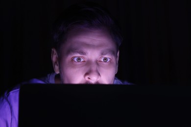 Photo of Man using computer at night, closeup. Internet addiction