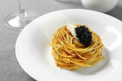 Tasty spaghetti with tomato sauce and black caviar served on table, closeup. Exquisite presentation of pasta dish