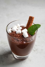 Photo of Cup of delicious hot chocolate with marshmallows, cinnamon stick and mint on light grey table