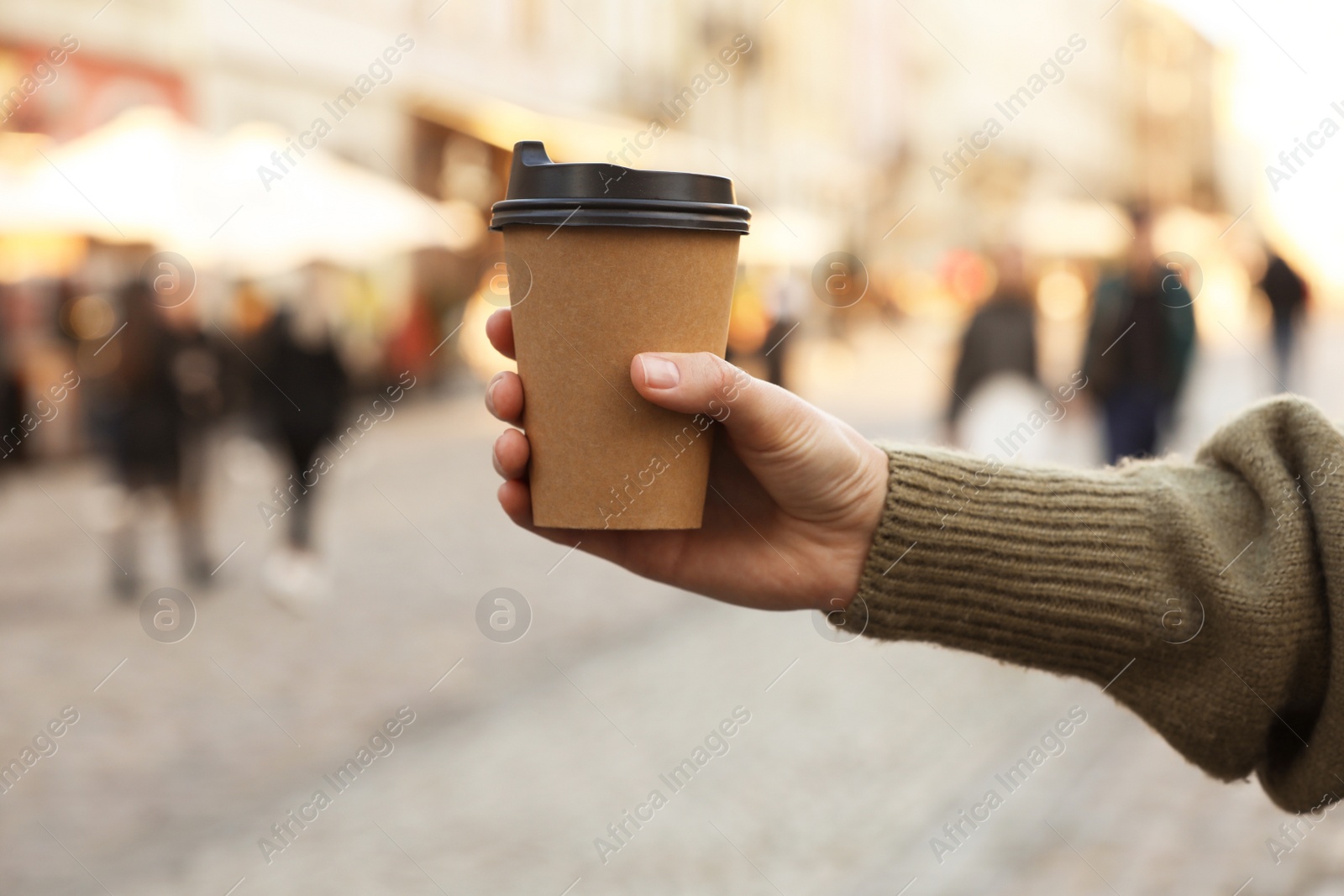 Photo of Woman holding paper takeaway cup on city street, closeup. Coffee to go