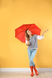 Woman with red umbrella near color wall