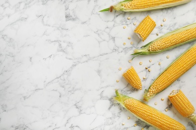 Photo of Tasty sweet corn cobs on marble table, top view