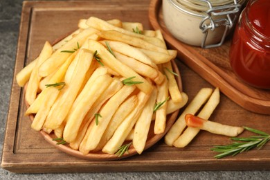 Photo of Delicious French fries served with sauces on grey textured table, closeup