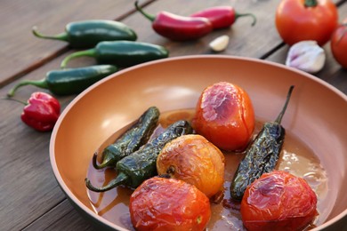 Frying pan with ingredients for salsa sauce on wooden table, closeup