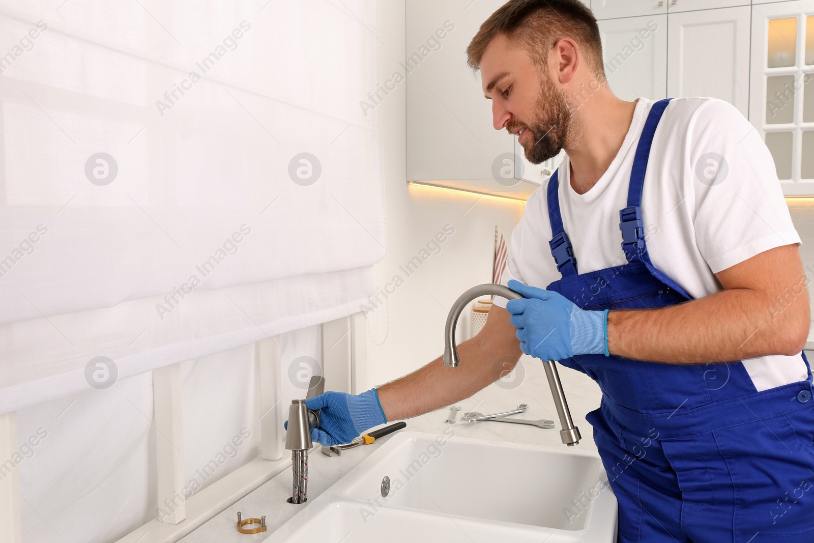 Photo of Professional plumber repairing water tap in kitchen